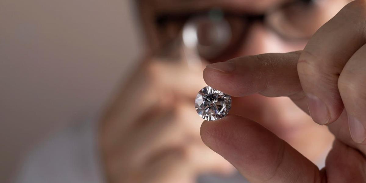 Close up of diamond dealer’s hands evaluating diamond.