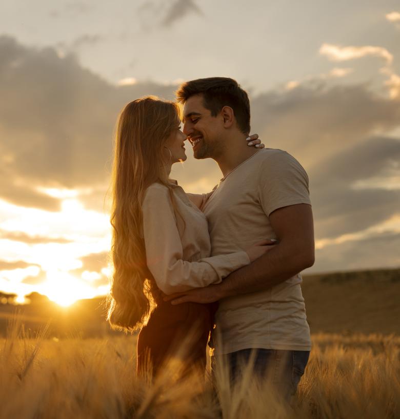 couple embracing in a field as sunset